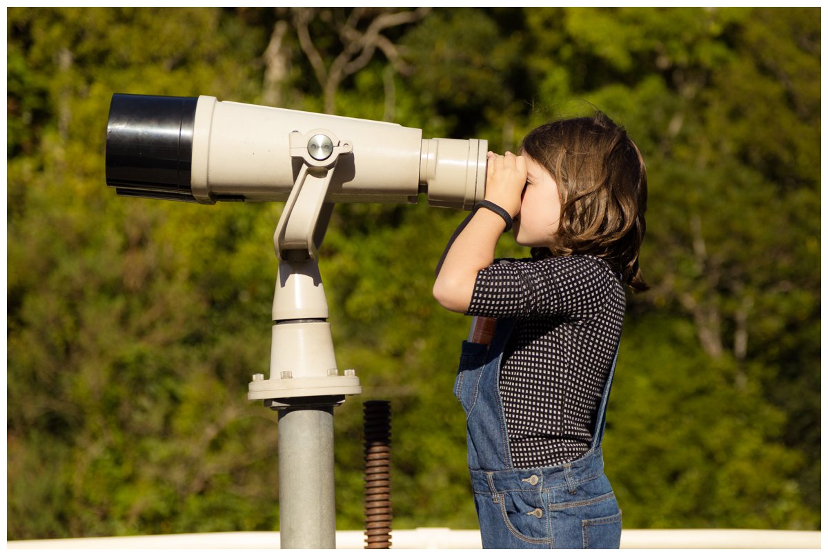Girl looks through huge binoculars at Zealandia