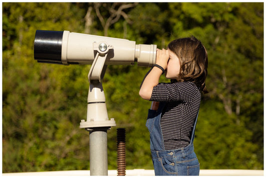 Girl looks through huge binoculars at Zealandia